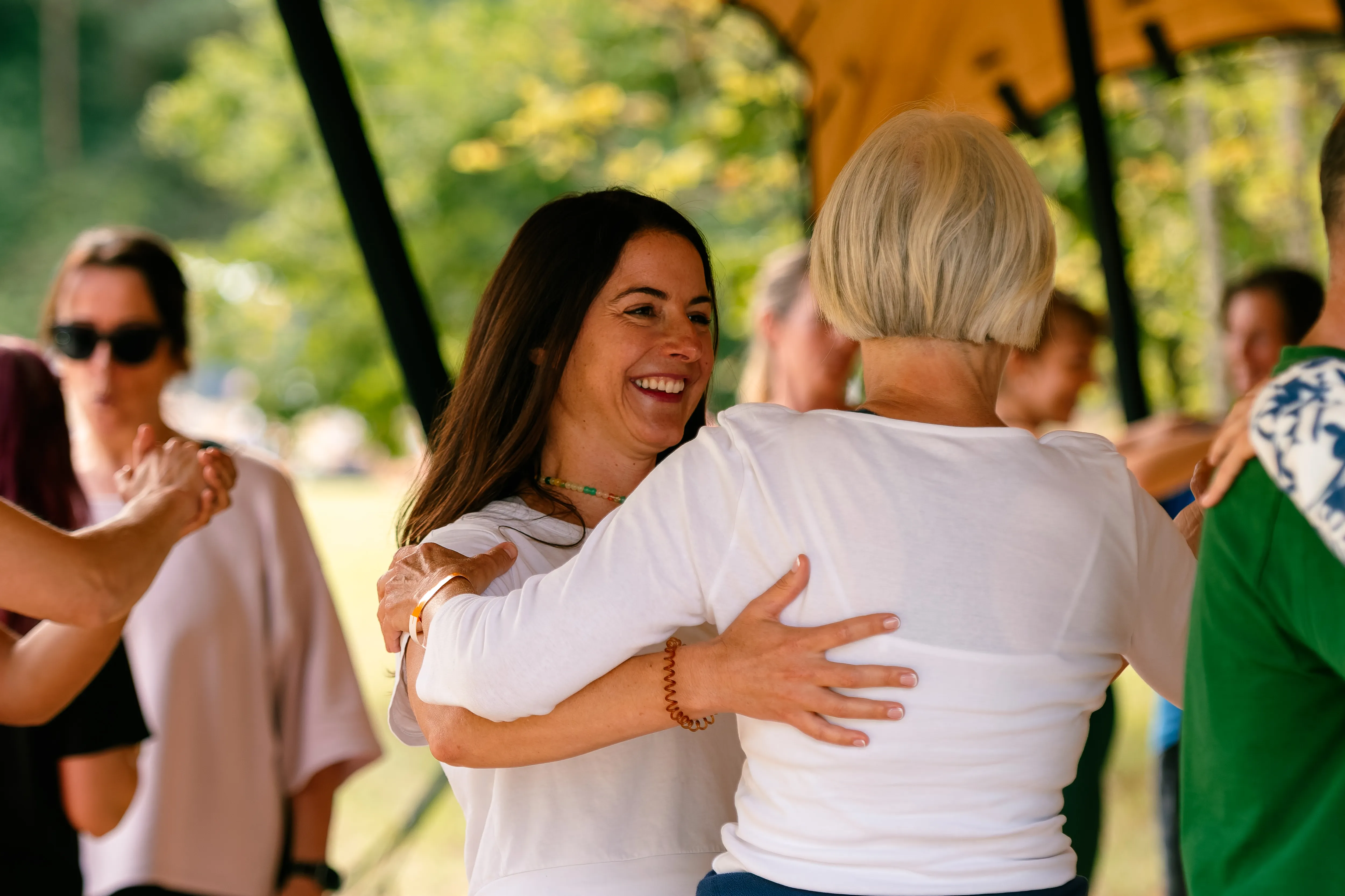 A dark-haired woman beaming as she partner-dances under the canopy.