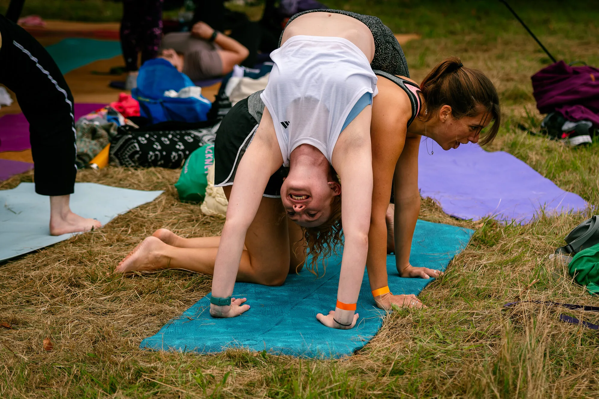A woman arching into a backbend on a yoga mat during an outdoor class.