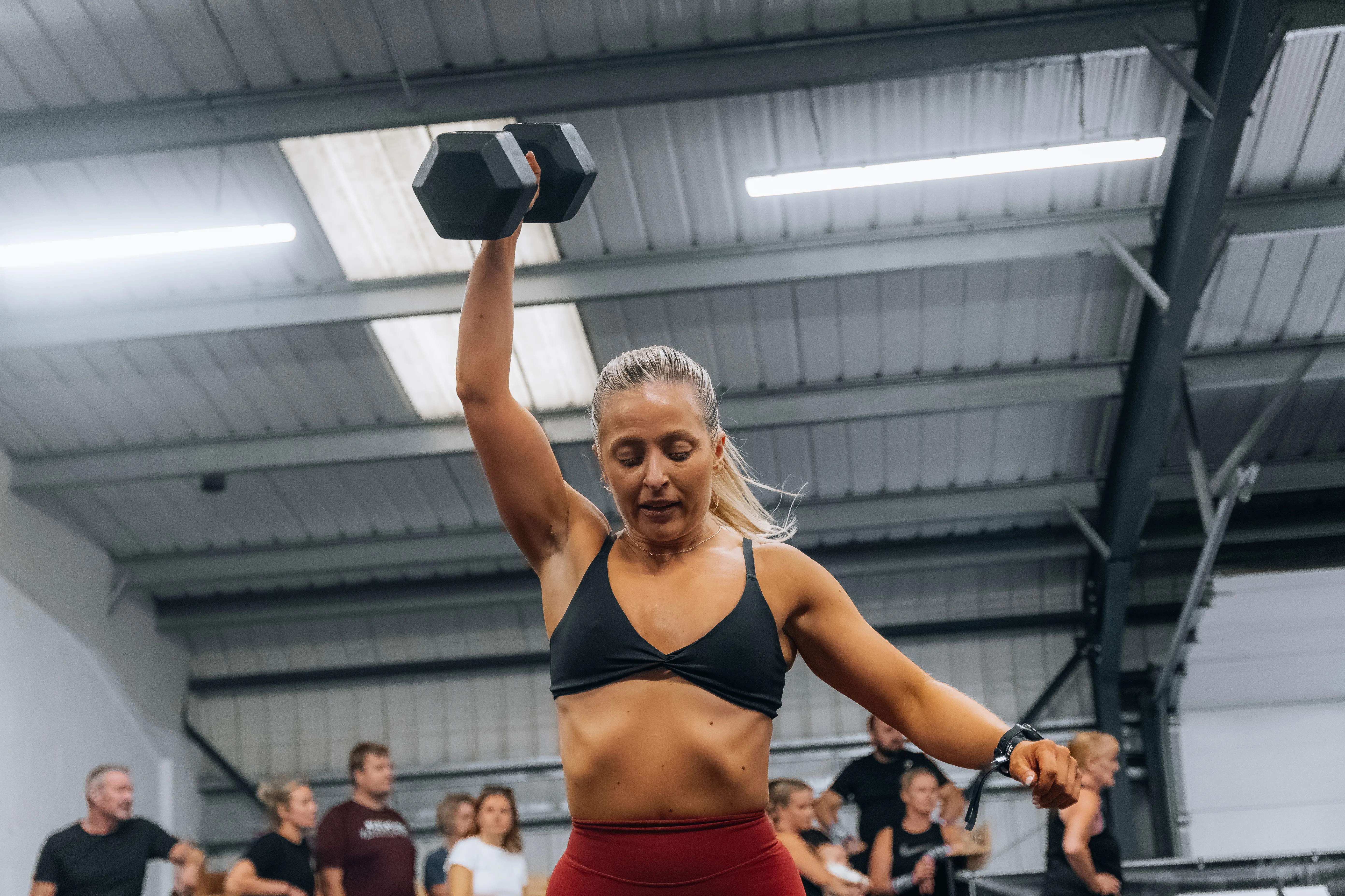 A competitor walking a dumbbell overhead down the track.
