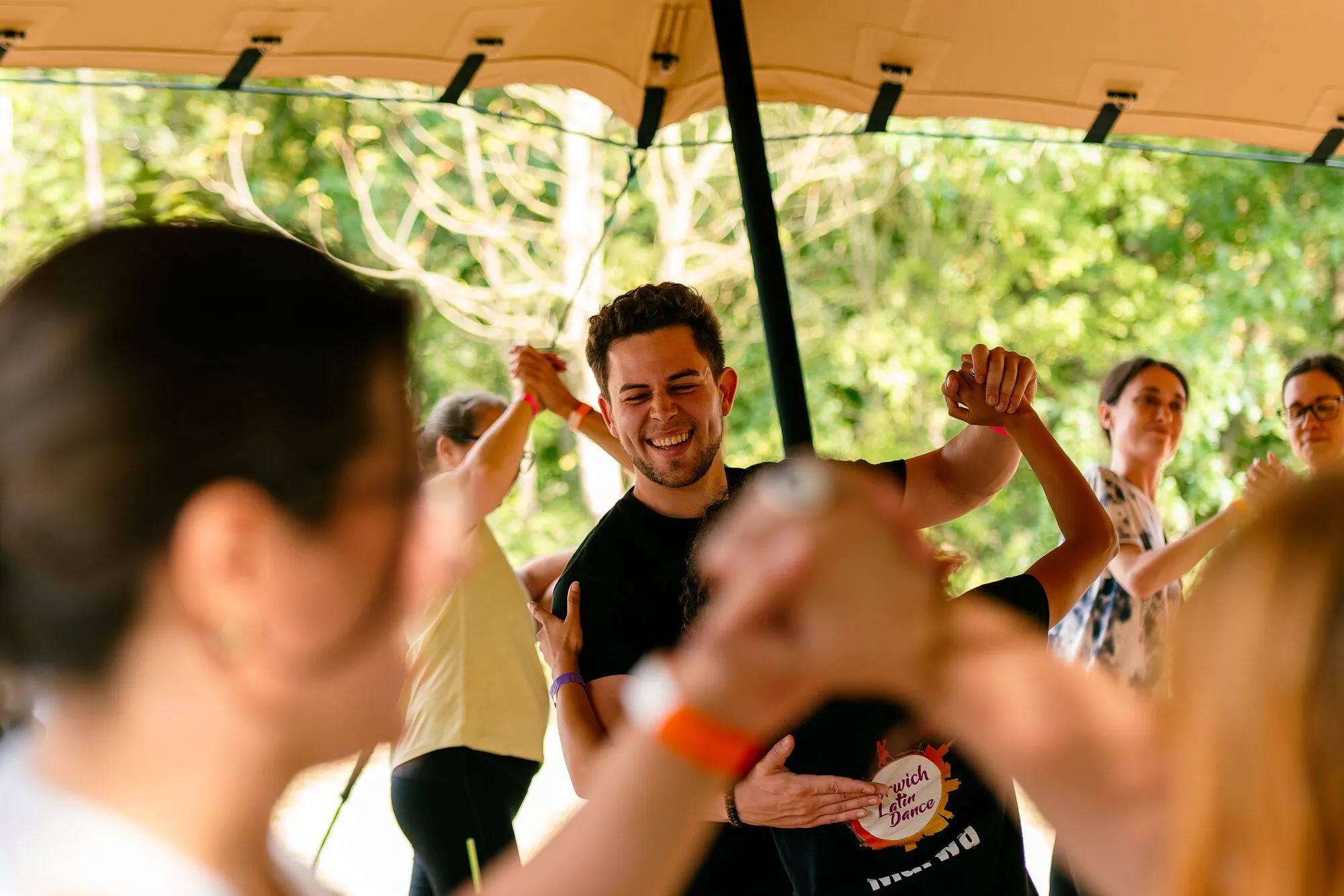A man dancing with his arms raised under a canopy at the festival.