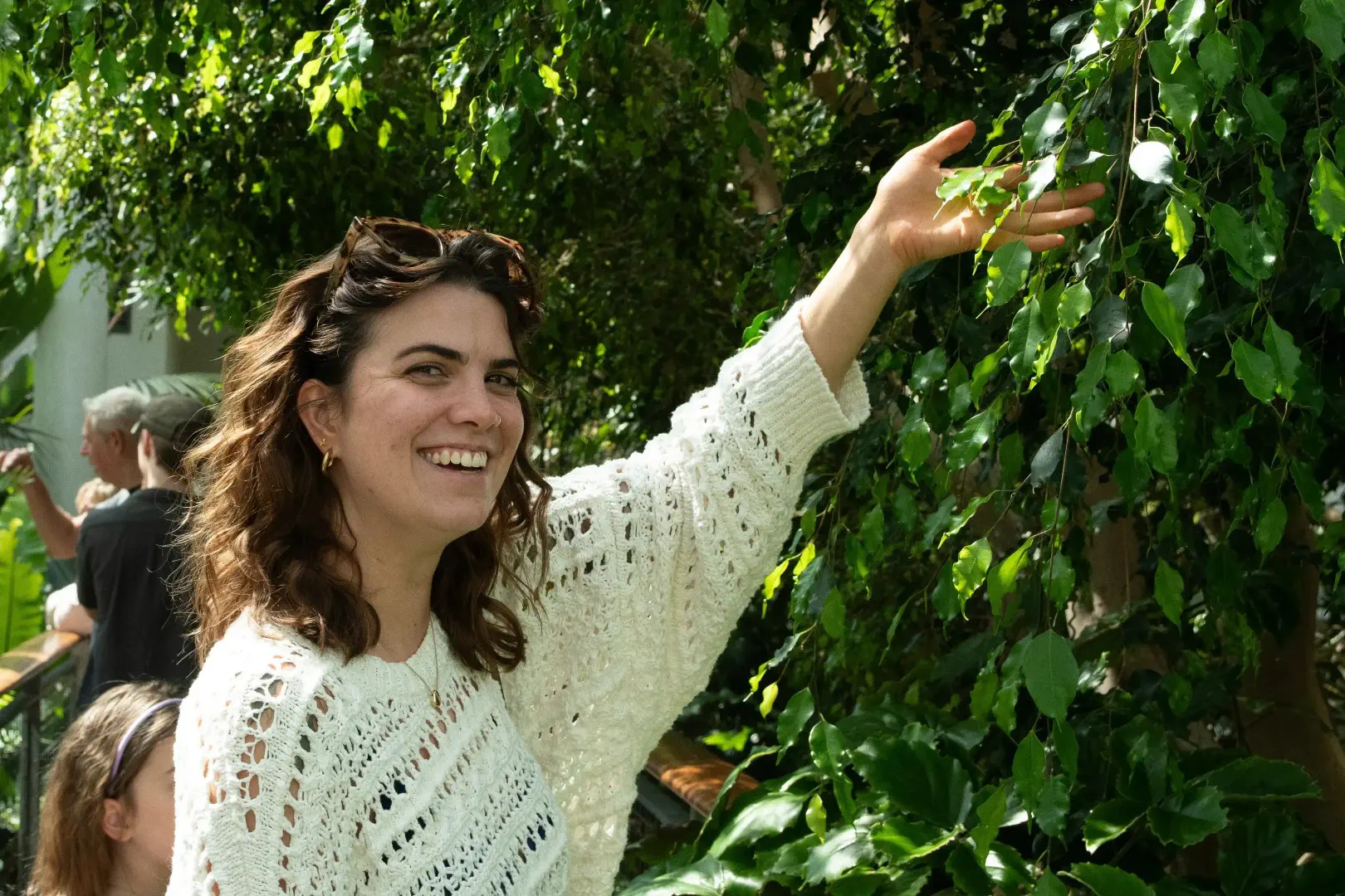 A young girl holding her arm up to a beautiful, luscious tree