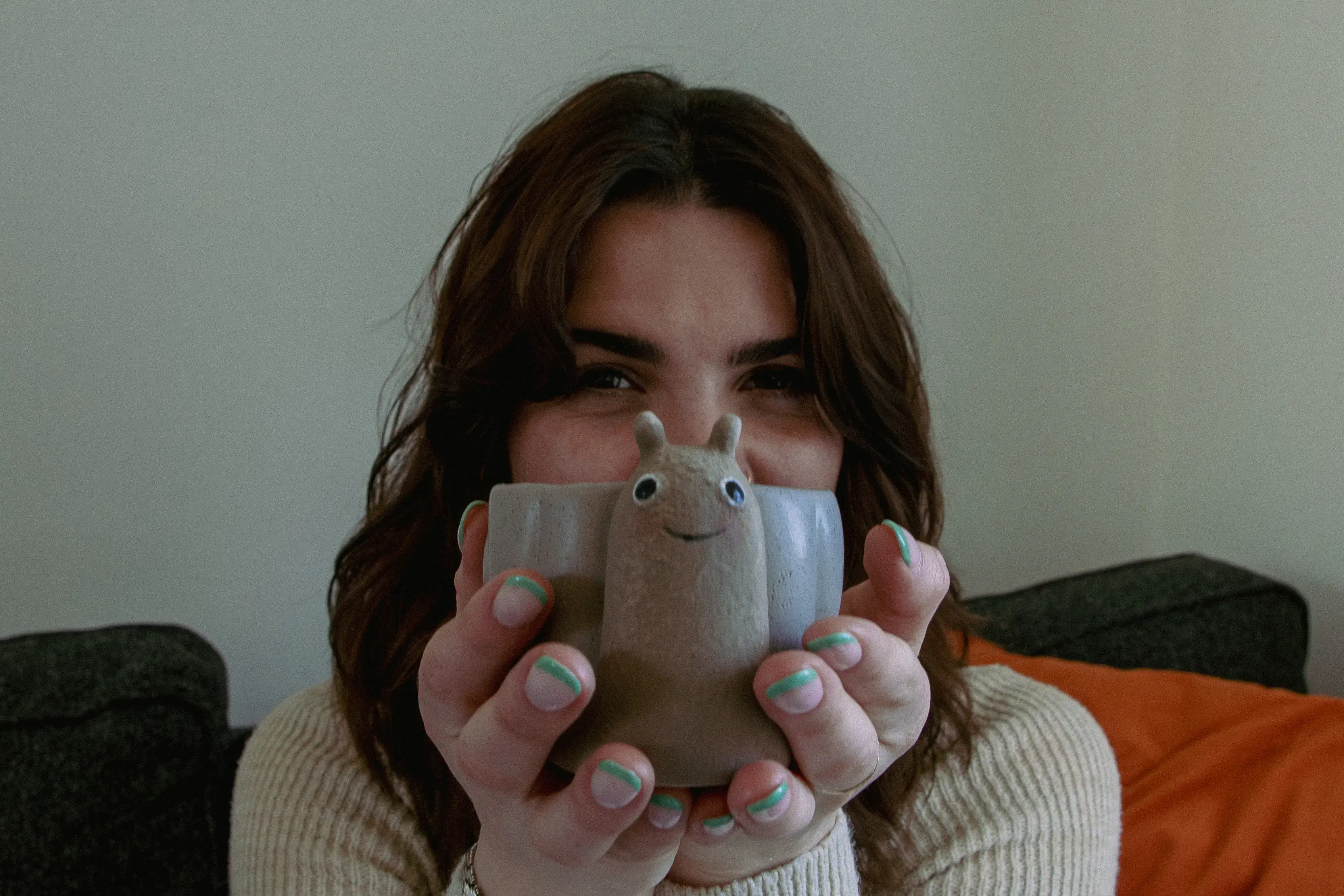 A young woman holding up a snail pen pot and smiling